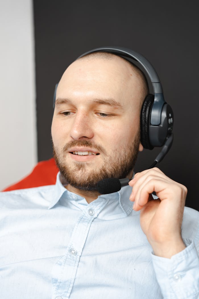 about-img A bald bearded man using headphones, depicting a modern call center operator in a professional setting.