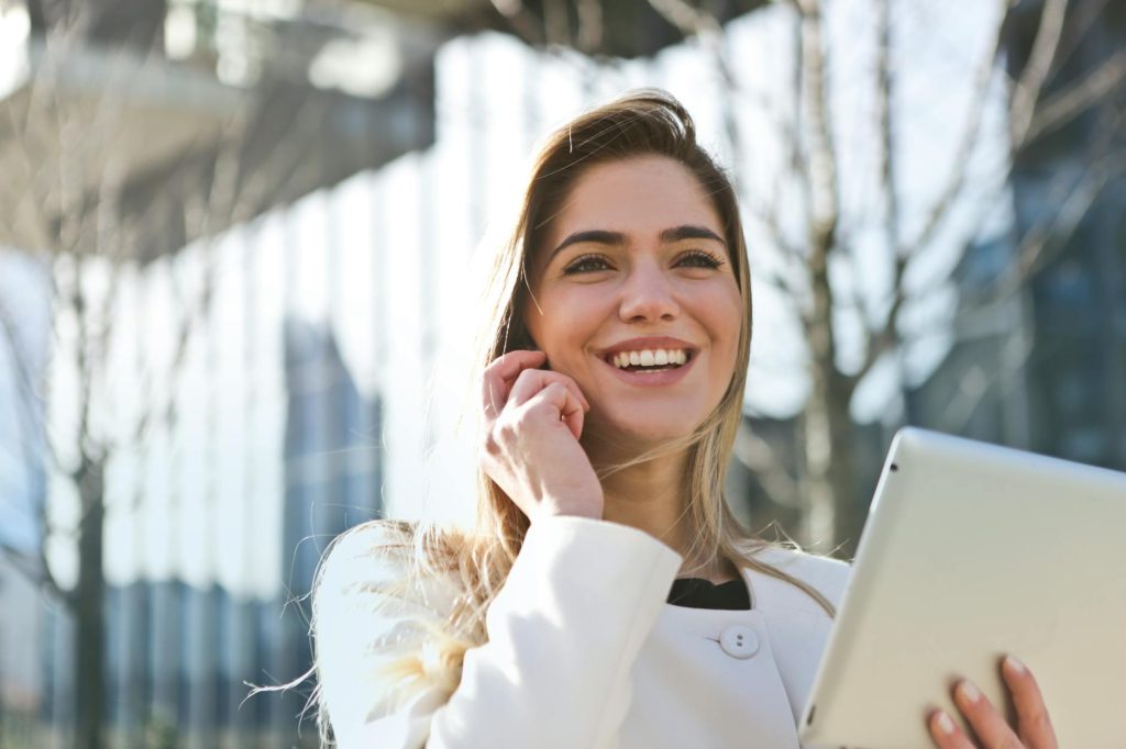 pexels photo 789822 789822 Confident businesswoman using her tablet and phone, smiling outdoors in sunlight.