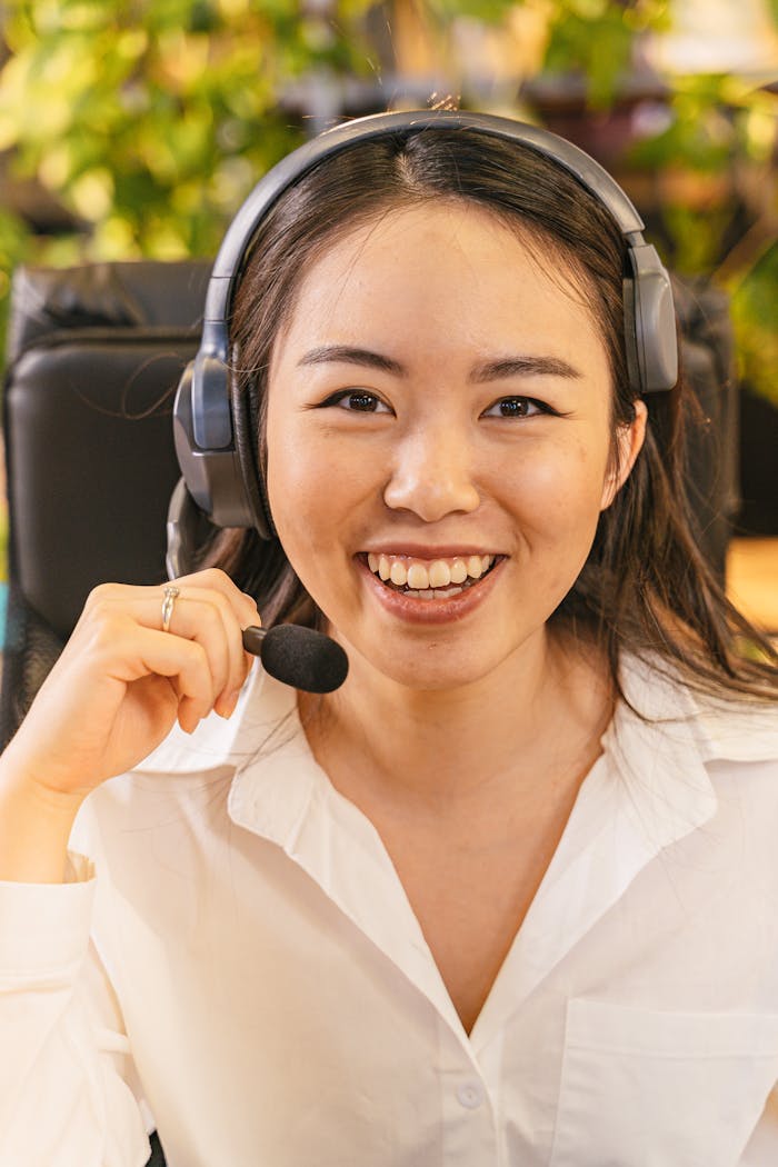 A young woman in an office setting wearing a headset, ready to assist over the phone.